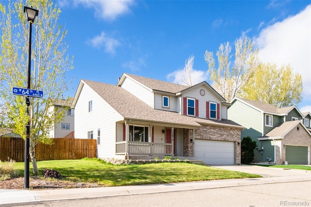 traditional home with fence, concrete driveway, a front lawn, and a garage