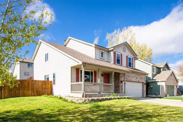 traditional home with a porch, fence, a front lawn, concrete driveway, and a shingled roof