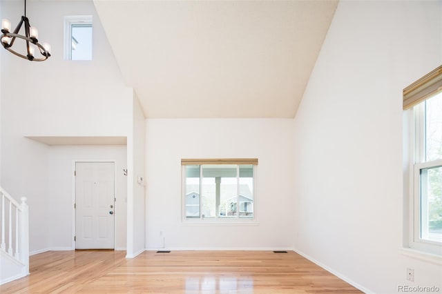 foyer featuring vaulted ceiling, a notable chandelier, stairway, and light wood-type flooring