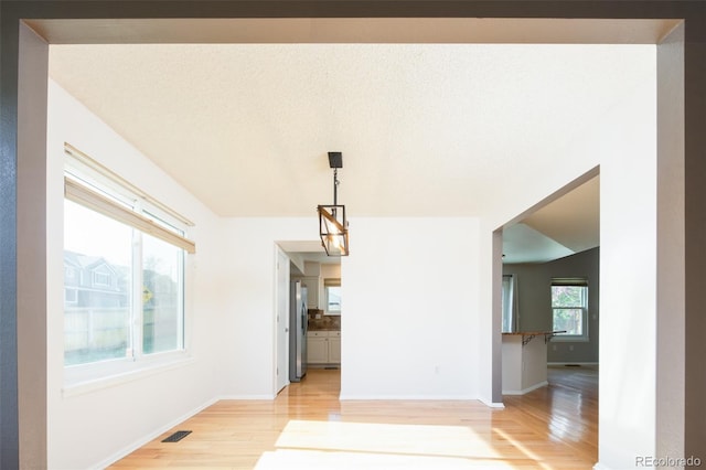 unfurnished dining area with baseboards, visible vents, and light wood-type flooring