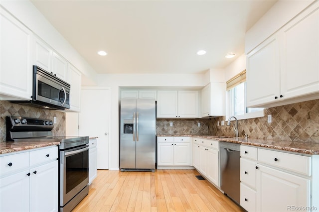 kitchen featuring a sink, decorative backsplash, light wood-style floors, and stainless steel appliances