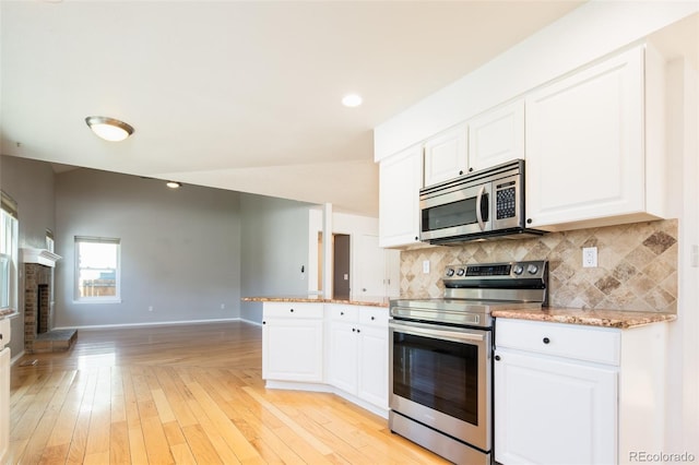 kitchen with white cabinets, appliances with stainless steel finishes, and decorative backsplash