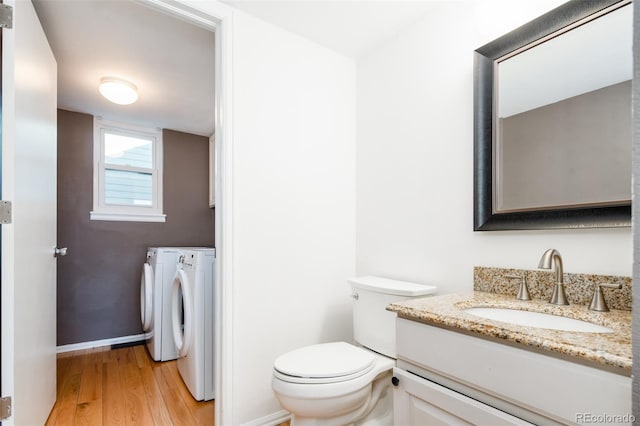 half bath featuring toilet, baseboards, washing machine and dryer, and wood finished floors