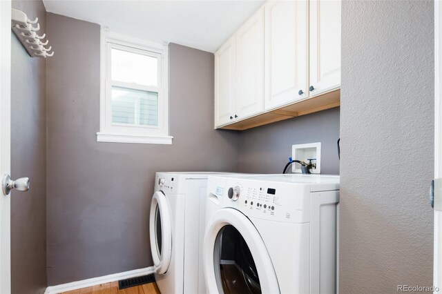 laundry room featuring baseboards, cabinet space, light wood finished floors, and washer and dryer
