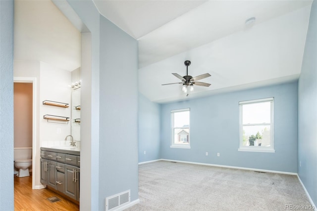 empty room with ceiling fan, visible vents, a sink, baseboards, and lofted ceiling