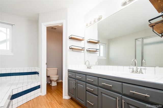 bathroom featuring double vanity, a sink, wood finished floors, and toilet
