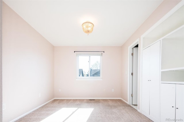 unfurnished bedroom with baseboards, light carpet, and a closet