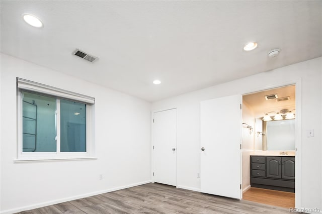 unfurnished bedroom with ensuite bath, visible vents, recessed lighting, and light wood-type flooring
