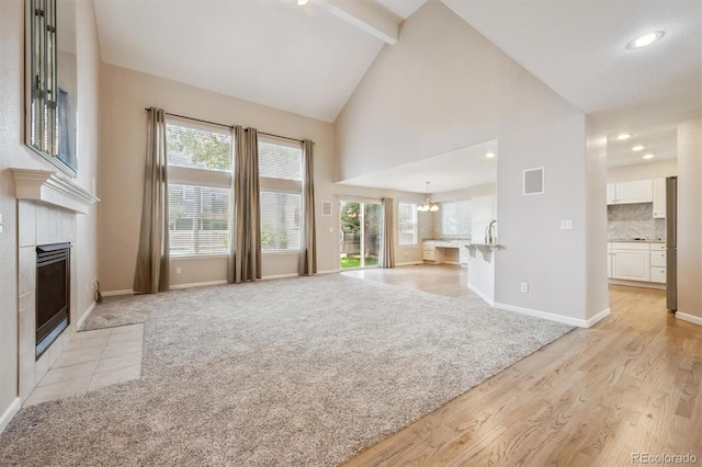 13540 Detroit St, Thornton, CO 80241 - unfurnished living room featuring a tile fireplace, beam ceiling, plenty of natural light, high vaulted ceiling, and light wood-style flooring