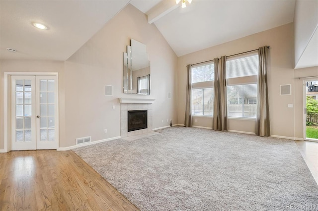 13540 Detroit St, Thornton, CO 80241 - unfurnished living room featuring a tile fireplace, beam ceiling, french doors, high vaulted ceiling, and carpet