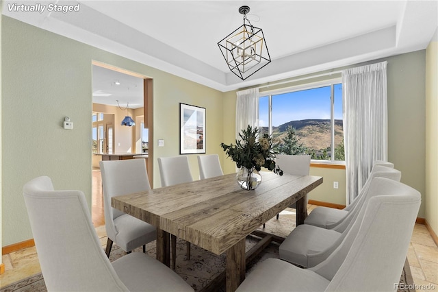 dining space featuring a mountain view, a raised ceiling, and a chandelier