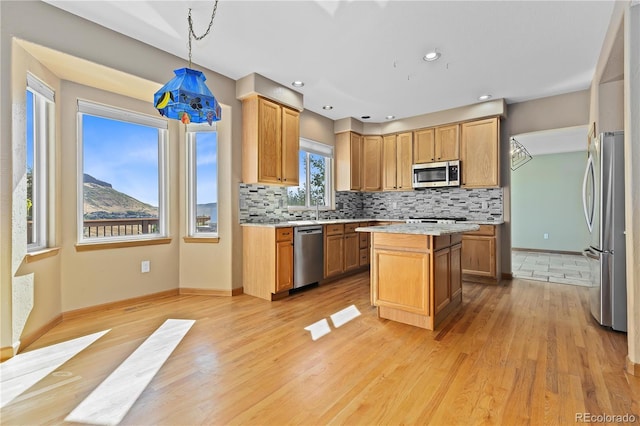 kitchen featuring light hardwood / wood-style flooring, hanging light fixtures, stainless steel appliances, a center island, and decorative backsplash