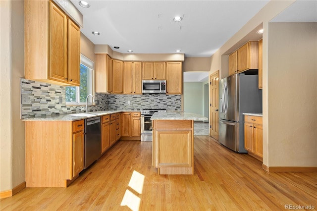 kitchen featuring a kitchen island, appliances with stainless steel finishes, sink, and light hardwood / wood-style flooring