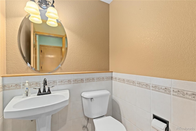 bathroom featuring toilet, sink, and tile walls