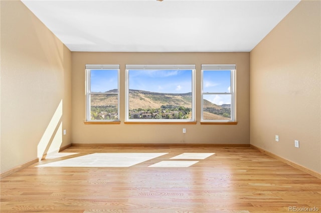 empty room featuring a mountain view and light wood-type flooring