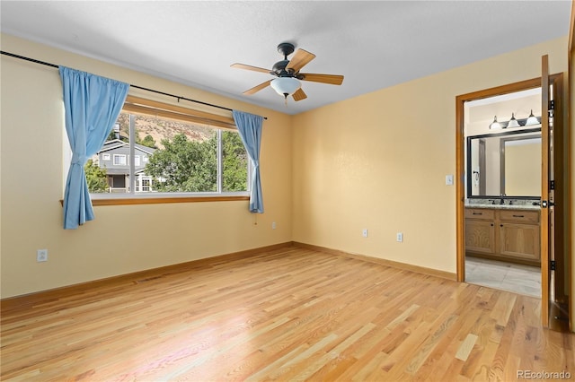 unfurnished bedroom featuring ensuite bathroom, ceiling fan, and light hardwood / wood-style flooring