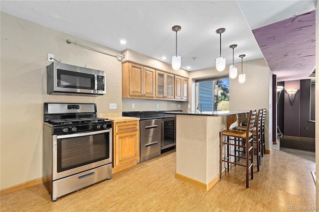 kitchen with decorative light fixtures, light wood-type flooring, a kitchen breakfast bar, and appliances with stainless steel finishes