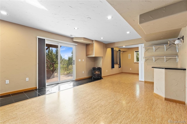 unfurnished living room featuring dark tile patterned floors and a wood stove