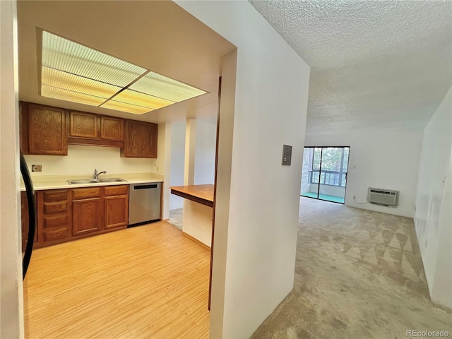 kitchen featuring stainless steel dishwasher, a sink, a textured ceiling, light countertops, and brown cabinets