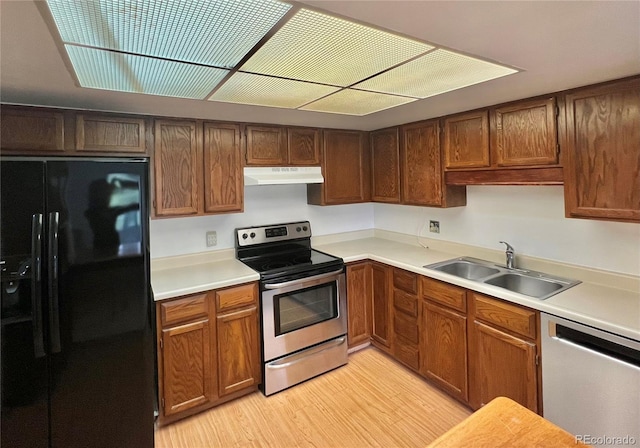 kitchen with stainless steel appliances, a sink, under cabinet range hood, light wood-style floors, and light countertops