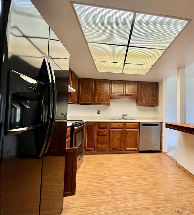 kitchen featuring appliances with stainless steel finishes, a sink, light wood-type flooring, and light countertops