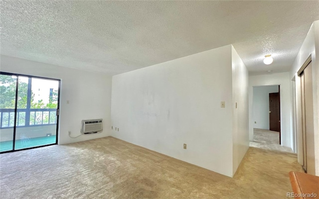 unfurnished room featuring light carpet, a textured ceiling, and an AC wall unit