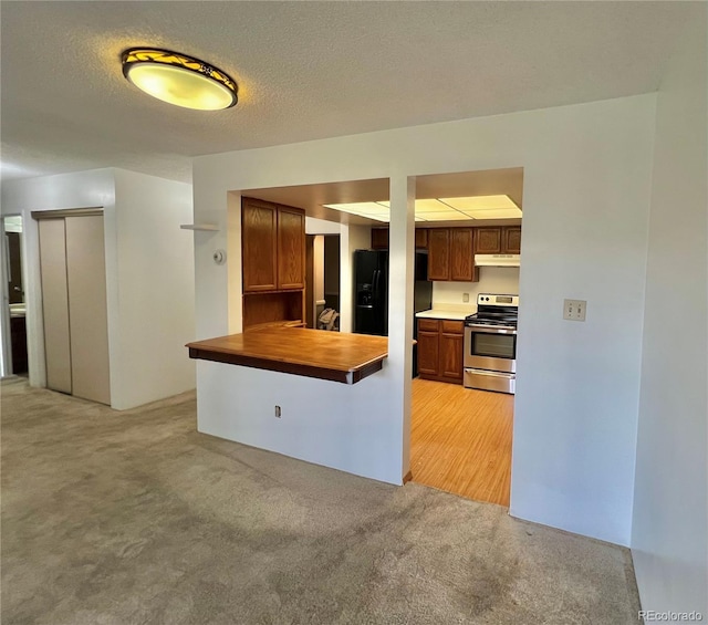kitchen with electric stove, under cabinet range hood, light colored carpet, black refrigerator with ice dispenser, and a peninsula