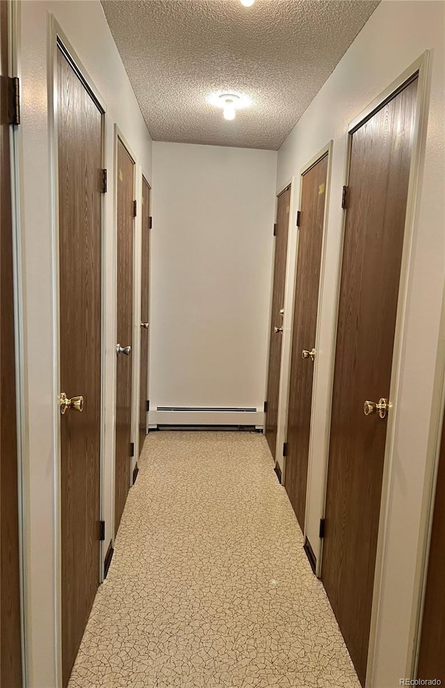 hall with a baseboard heating unit and a textured ceiling