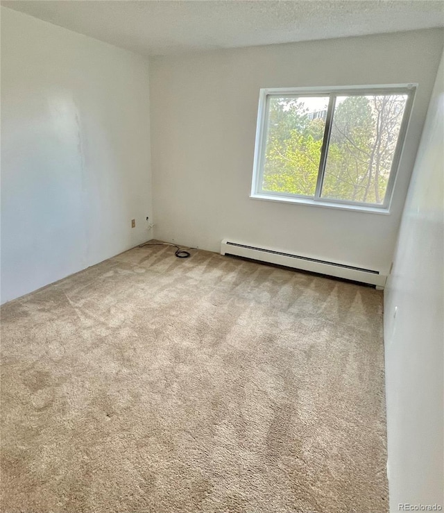 empty room featuring a baseboard heating unit and carpet floors