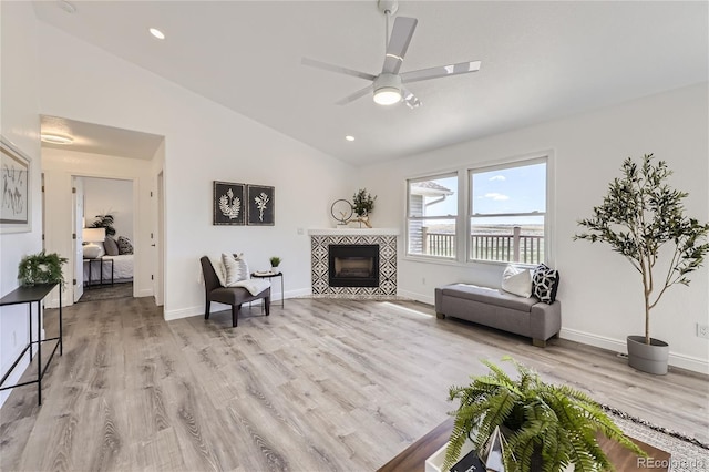 living room featuring a fireplace, light hardwood / wood-style floors, ceiling fan, and lofted ceiling