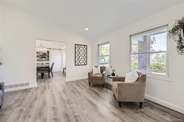 sitting room with wood-type flooring, lofted ceiling, and an inviting chandelier