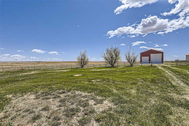 view of yard featuring a garage, a rural view, and an outbuilding