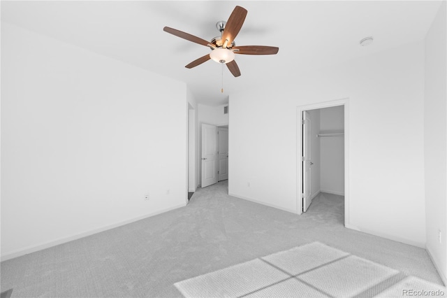 unfurnished bedroom with light carpet, a closet, ceiling fan, and a spacious closet