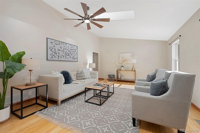 living room with wood-type flooring, ceiling fan, and vaulted ceiling with skylight