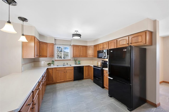 kitchen with brown cabinets, decorative light fixtures, light countertops, a sink, and black appliances