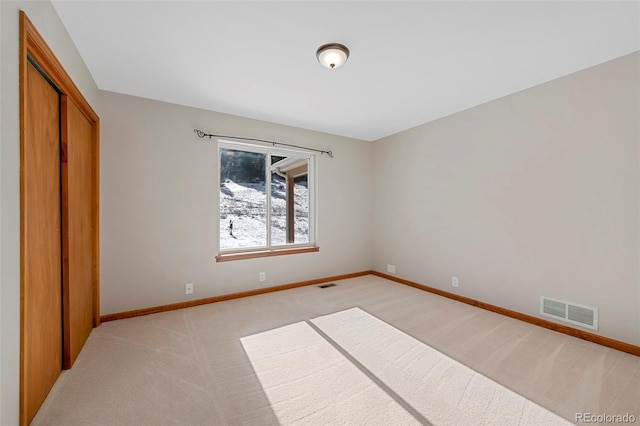 empty room with visible vents, light carpet, and baseboards