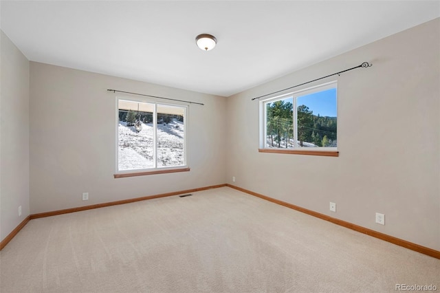 empty room featuring visible vents, baseboards, and carpet flooring