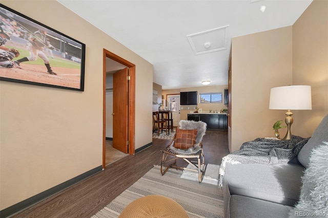 living area featuring attic access, baseboards, and dark wood-type flooring