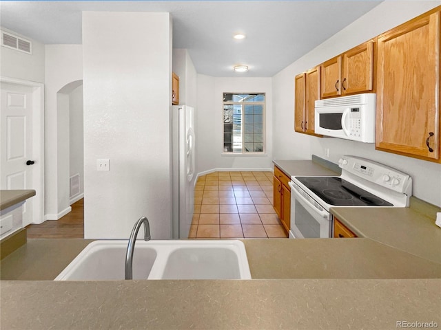 kitchen with sink, white appliances, and light tile patterned flooring