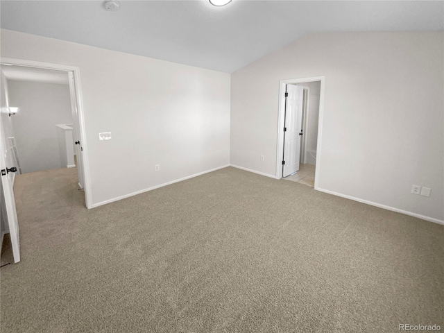 unfurnished bedroom featuring light carpet, ensuite bathroom, and lofted ceiling