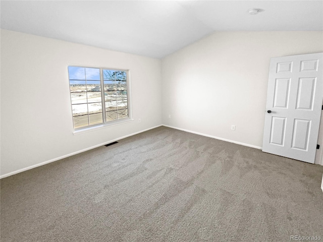 spare room featuring carpet and lofted ceiling