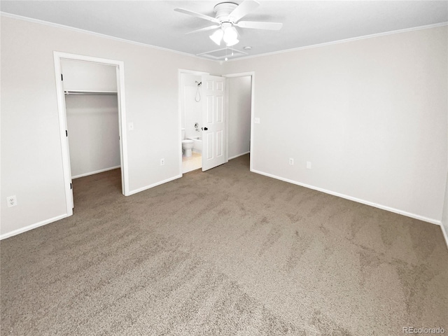 unfurnished bedroom with ceiling fan, ensuite bath, a walk in closet, and dark colored carpet