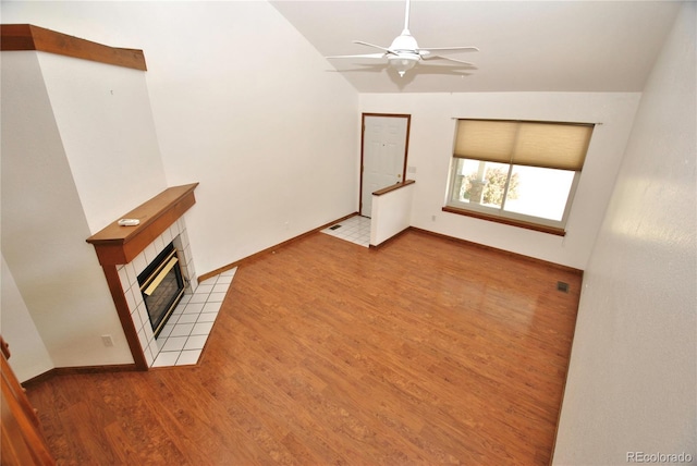 unfurnished living room with baseboards, a ceiling fan, vaulted ceiling, light wood-style floors, and a fireplace