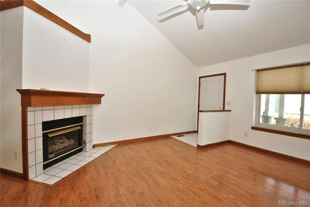 unfurnished living room featuring baseboards, ceiling fan, wood finished floors, a fireplace, and high vaulted ceiling