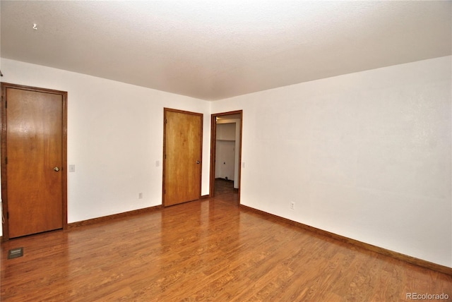 unfurnished bedroom with baseboards, visible vents, and wood finished floors