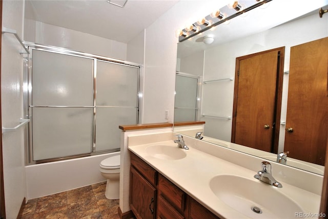 full bathroom with toilet, shower / bath combination with glass door, double vanity, and a sink