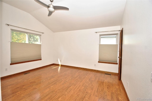 spare room featuring ceiling fan, wood finished floors, visible vents, baseboards, and vaulted ceiling