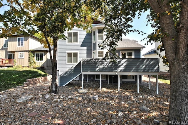 back of property featuring stairway, a wooden deck, and a lawn