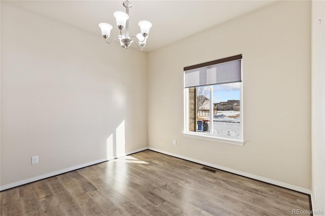 empty room with hardwood / wood-style flooring and a chandelier