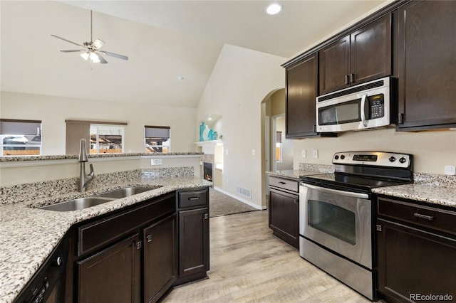 kitchen featuring sink, vaulted ceiling, dark brown cabinets, light wood-type flooring, and stainless steel appliances